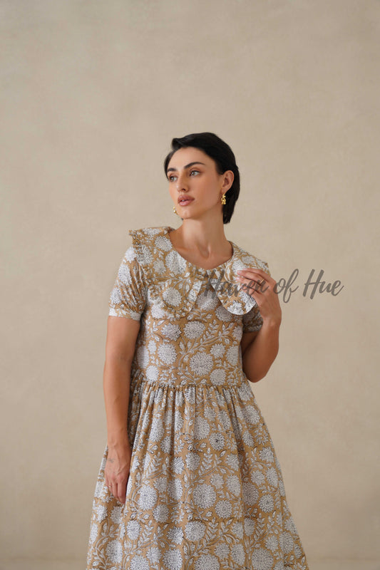 Front view of a model wearing a beige and white floral cotton midi dress with a large ruffle collar.