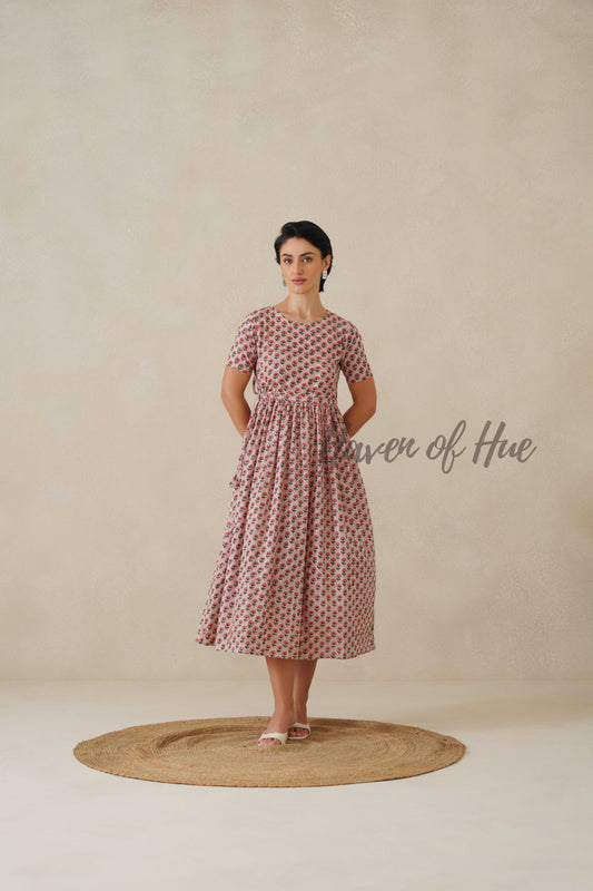 Front view of a woman wearing a deep berry pink cotton midi dress with white and red botanical floral prints and short sleeves.