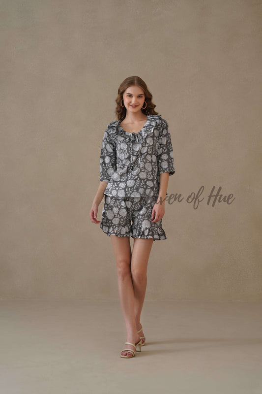 A woman modeling a black and white floral hand block print cotton co-ord set with a ruffled neckline.