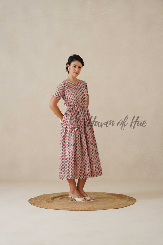 Side profile of a woman in a magenta pink floral midi dress showing the flowy A-line silhouette and functional side pockets.