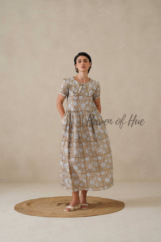 Model posing in a beige floral cotton dress with gold earrings for a sophisticated cottagecore look.